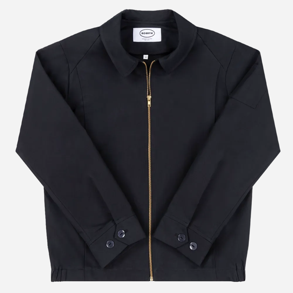 Robbyn unisex black workwear jacket shown from the front, featuring a boxy fit, reinforced seams, adjustable buttoned cuffs, and minimal detailing.