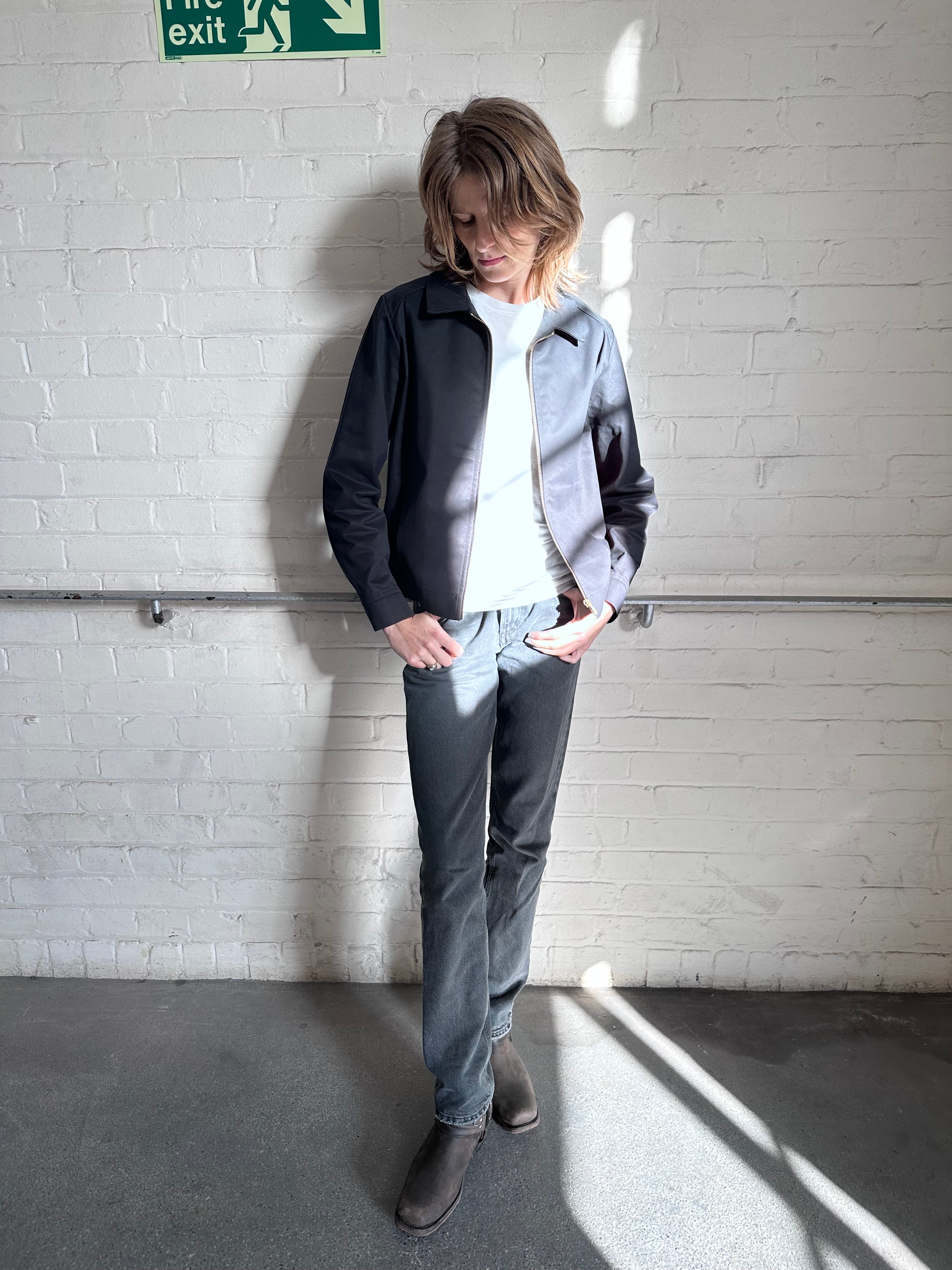 Female model wearing the Robbyn black Mechano workwear jacket, styled with a white T-shirt, grey jeans in London.