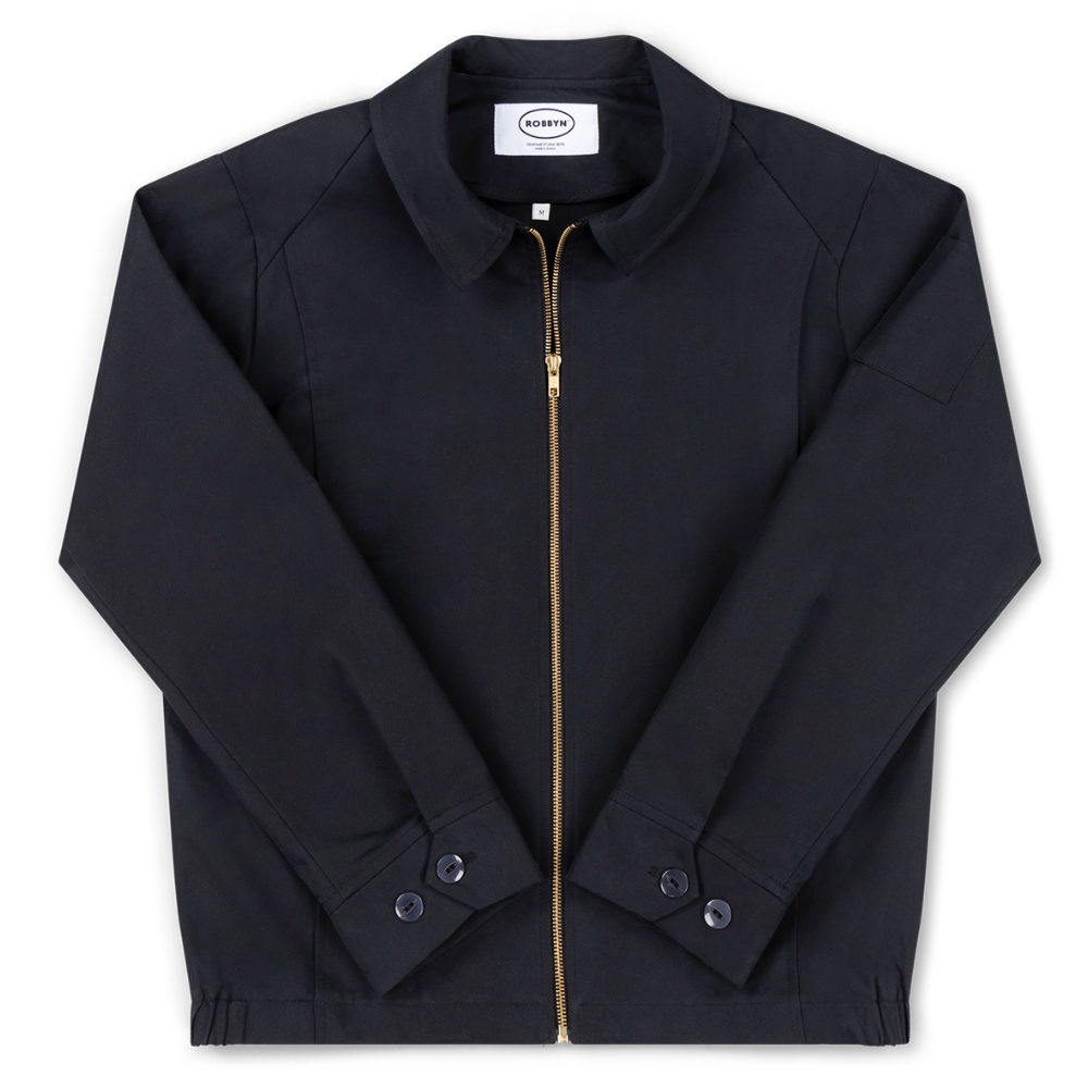 Robbyn unisex black workwear jacket shown from the front, featuring a boxy fit, reinforced seams, adjustable buttoned cuffs, and minimal detailing.