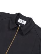 Close-up detail of the jacket’s metal zip and collar on the black workwear-style jacket.